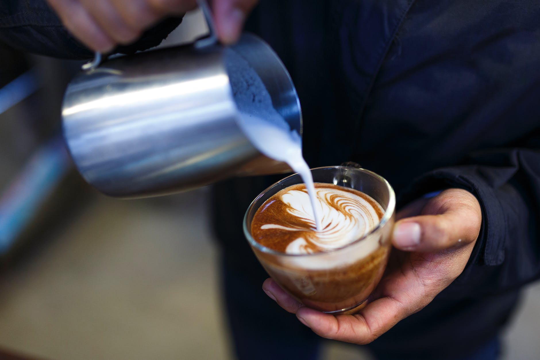 person pouring milk on coffee